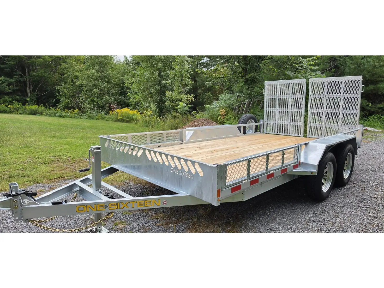 Galvanized tandem axle open rail utility trailer, three-quarter front view with the mesh ramps stowed upright