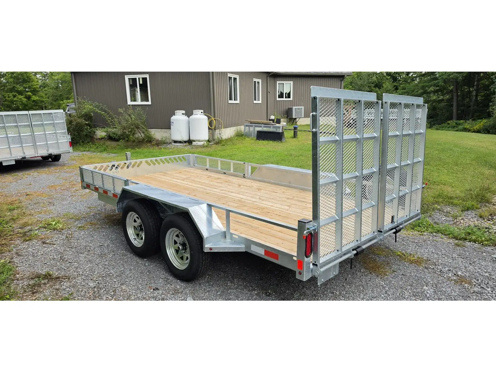 Three-quarter rear view showing the split mesh ramp gates and tandem galvanized wheels